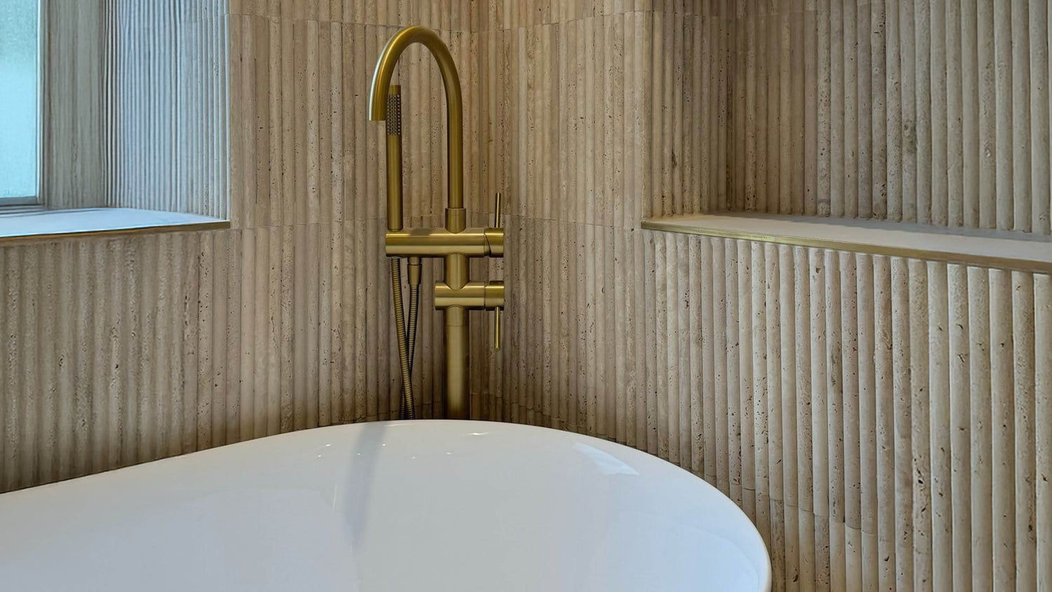 Gold faucet over a white bathtub in a bathroom with wooden walls.